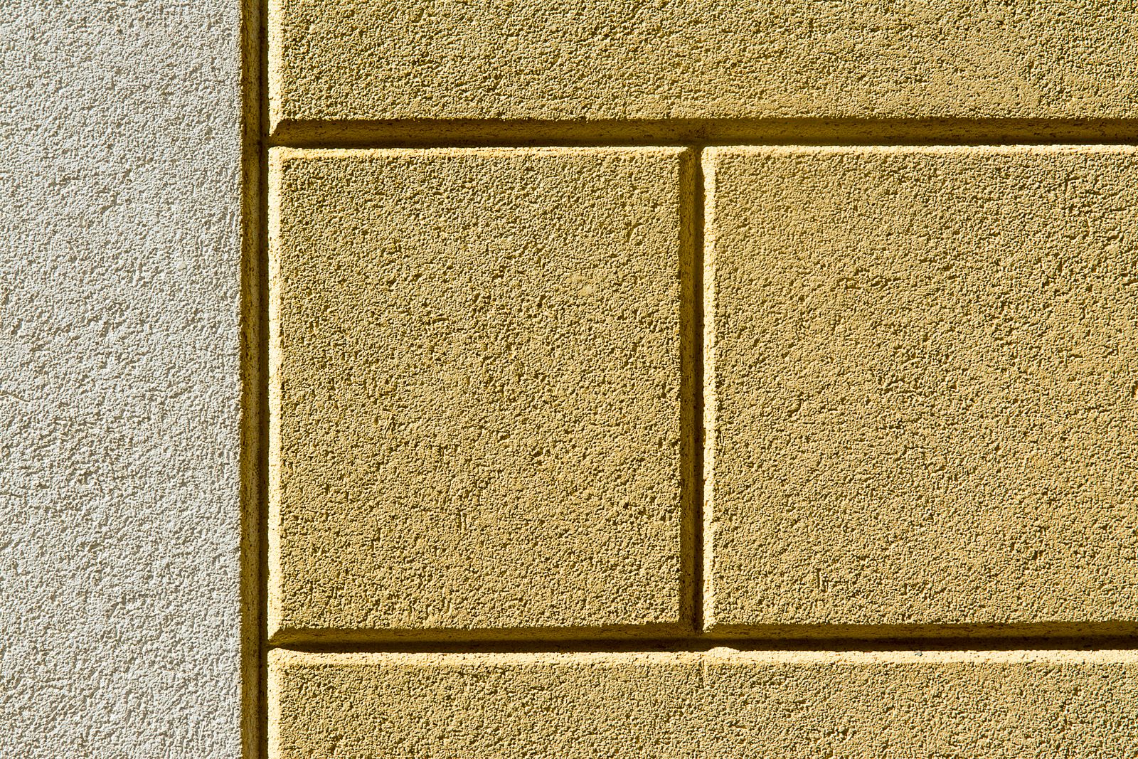 Gros plan sur la texture d'un enduit de façade peint en jaune